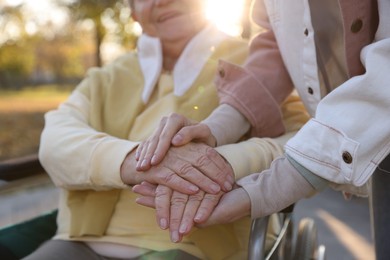 Photo of Caregiver with elderly woman in wheelchair at park, closeup