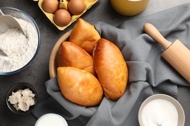 Photo of Delicious pirozhki (stuffed pastry pies) and ingredients on grey table, flat lay