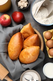 Photo of Delicious pirozhki (stuffed pastry pies) and ingredients on grey table, flat lay