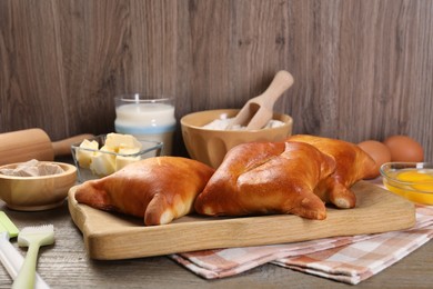 Photo of Delicious pirozhki (stuffed pastry pies) and ingredients on wooden table