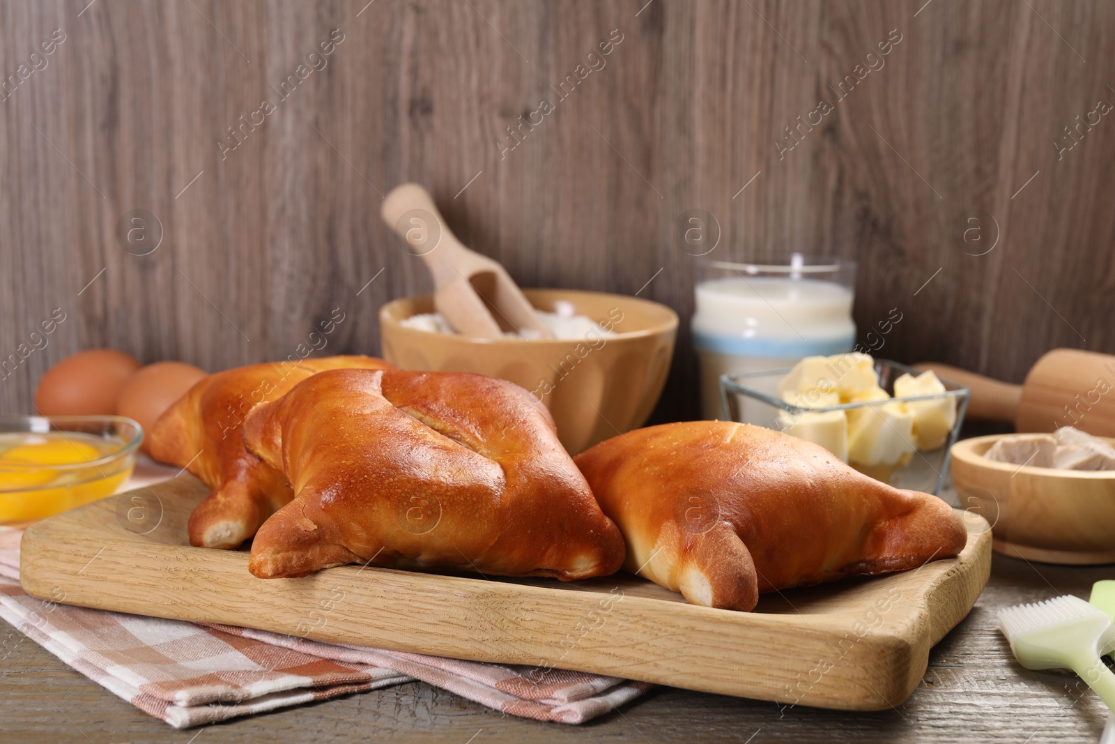 Photo of Delicious pirozhki (stuffed pastry pies) and ingredients on wooden table