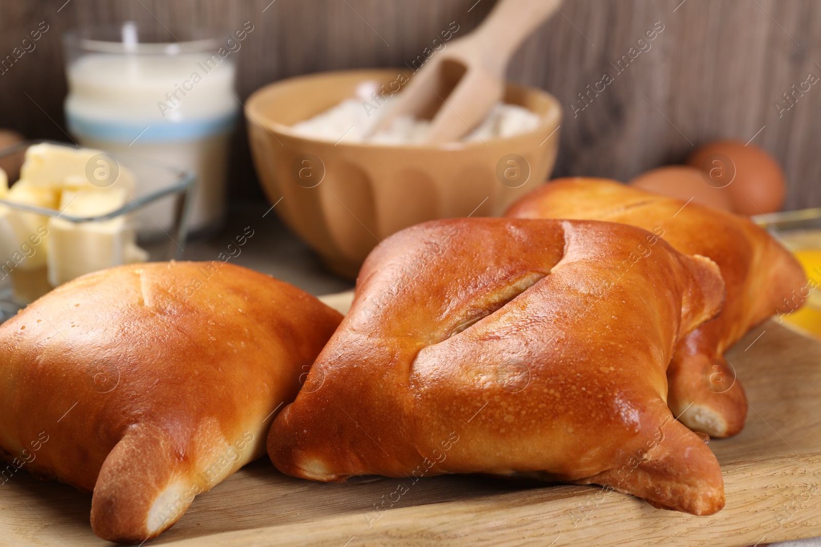 Photo of Delicious pirozhki (stuffed pastry pies) and ingredients on wooden table, closeup