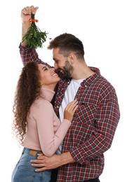 Lovely couple under mistletoe bunch on white background