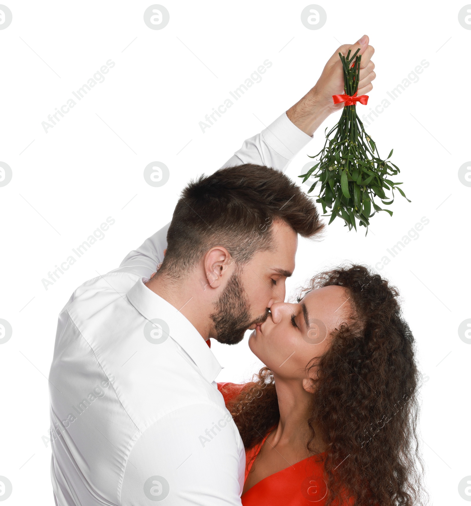 Photo of Happy couple kissing under mistletoe bunch on white background