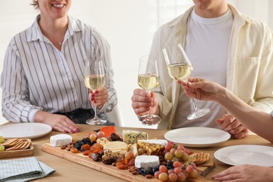 Photo of People with glasses of wine at served table, closeup