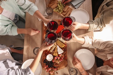 Photo of People clinking glasses of red wine at served table, top view