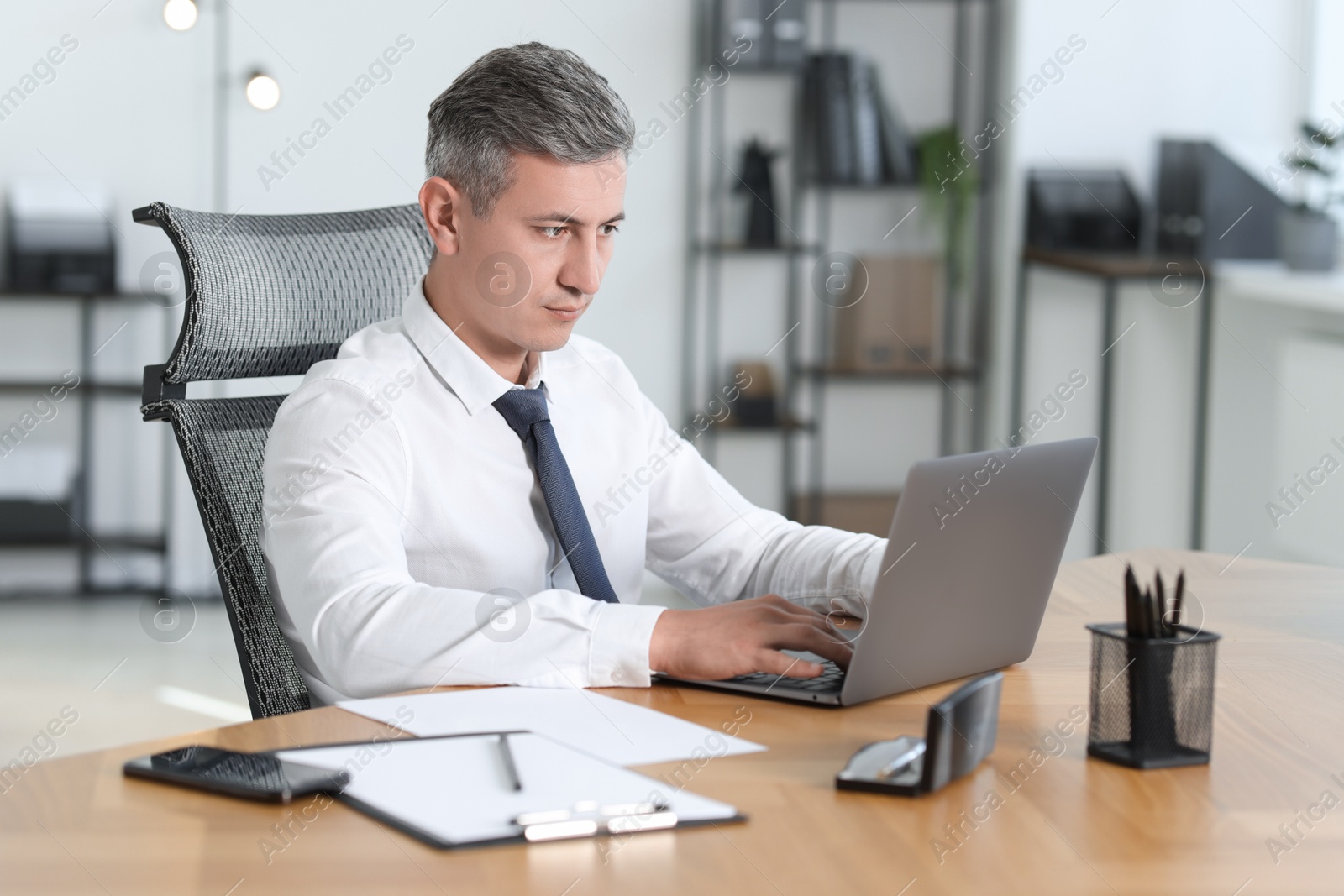 Photo of Businessman working on laptop at table in office