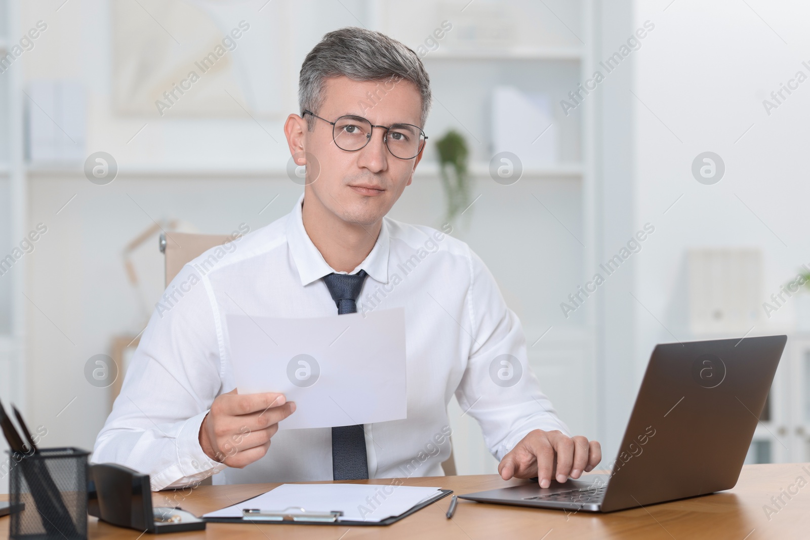 Photo of Businessman working on laptop at table in office