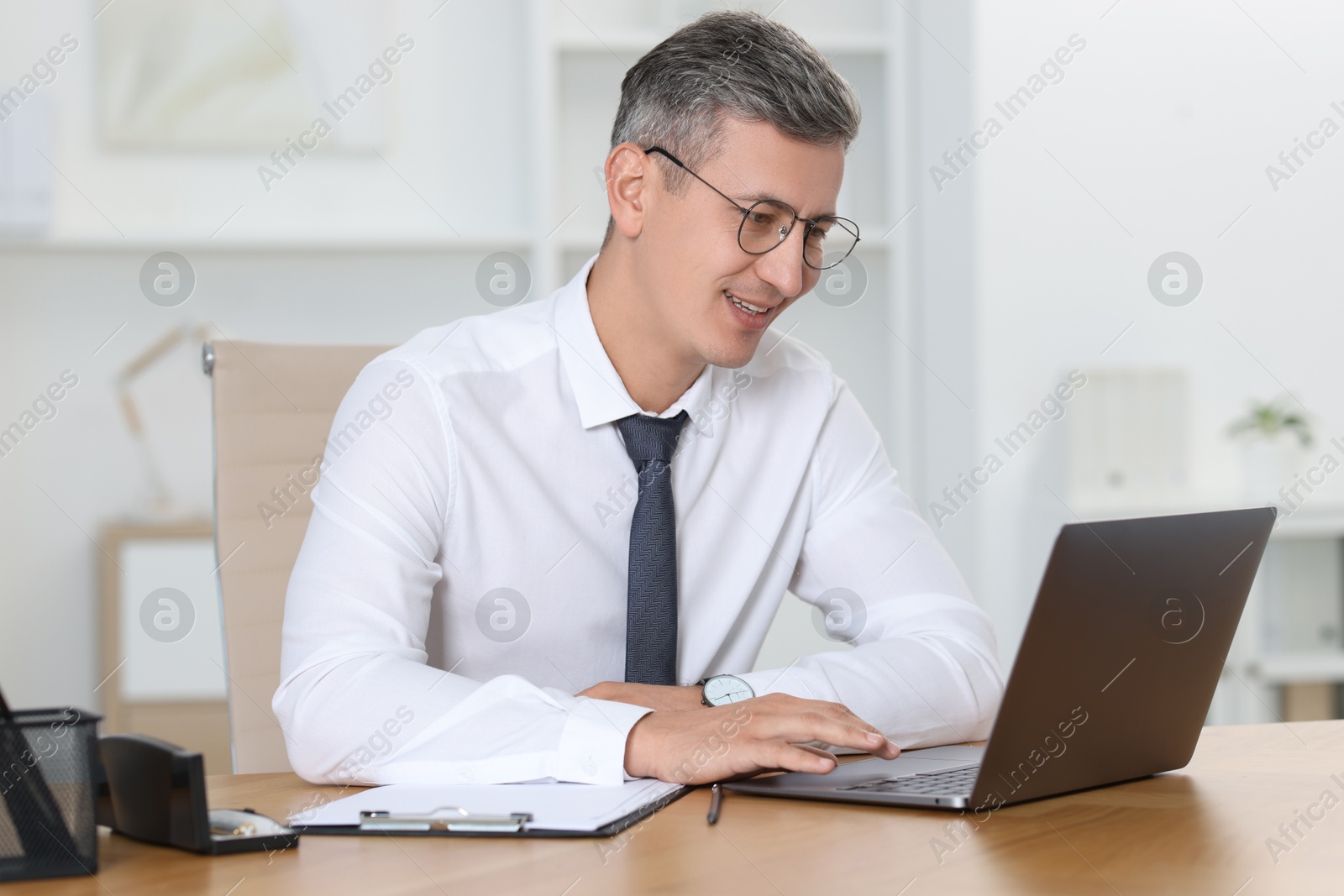 Photo of Businessman working on laptop at table in office