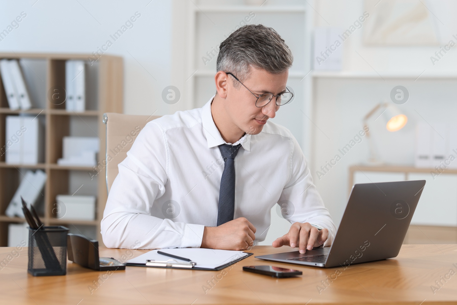 Photo of Businessman working on laptop at table in office