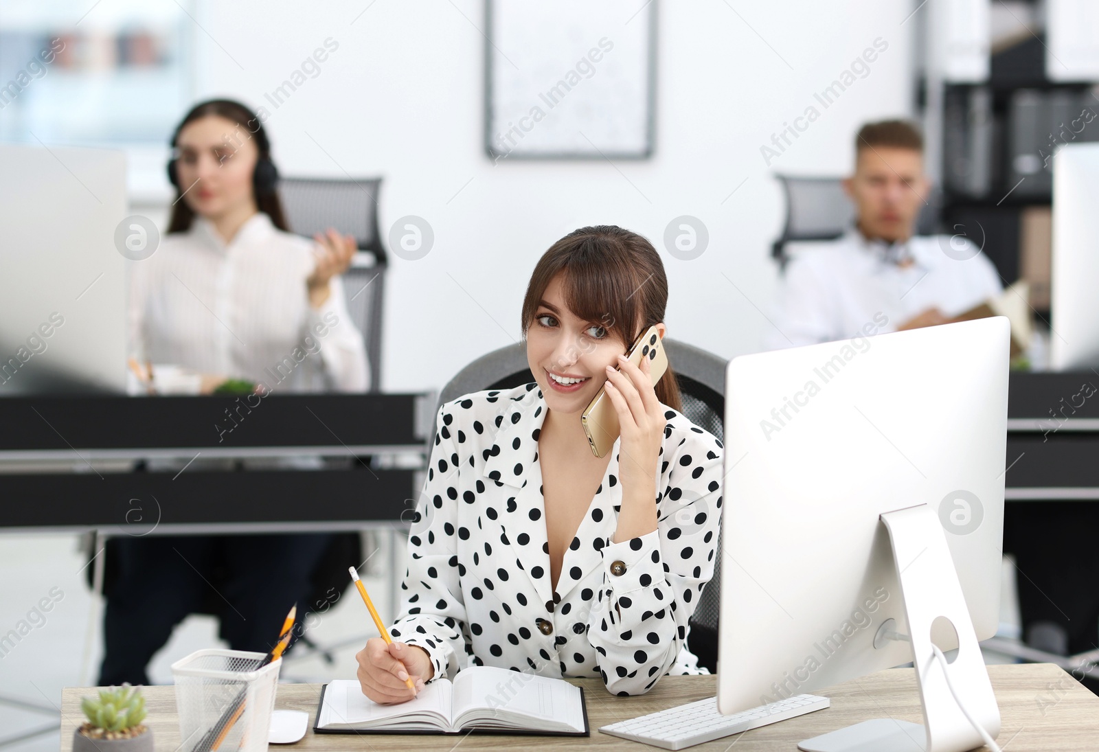 Photo of Saleswoman talking on phone at desk in office