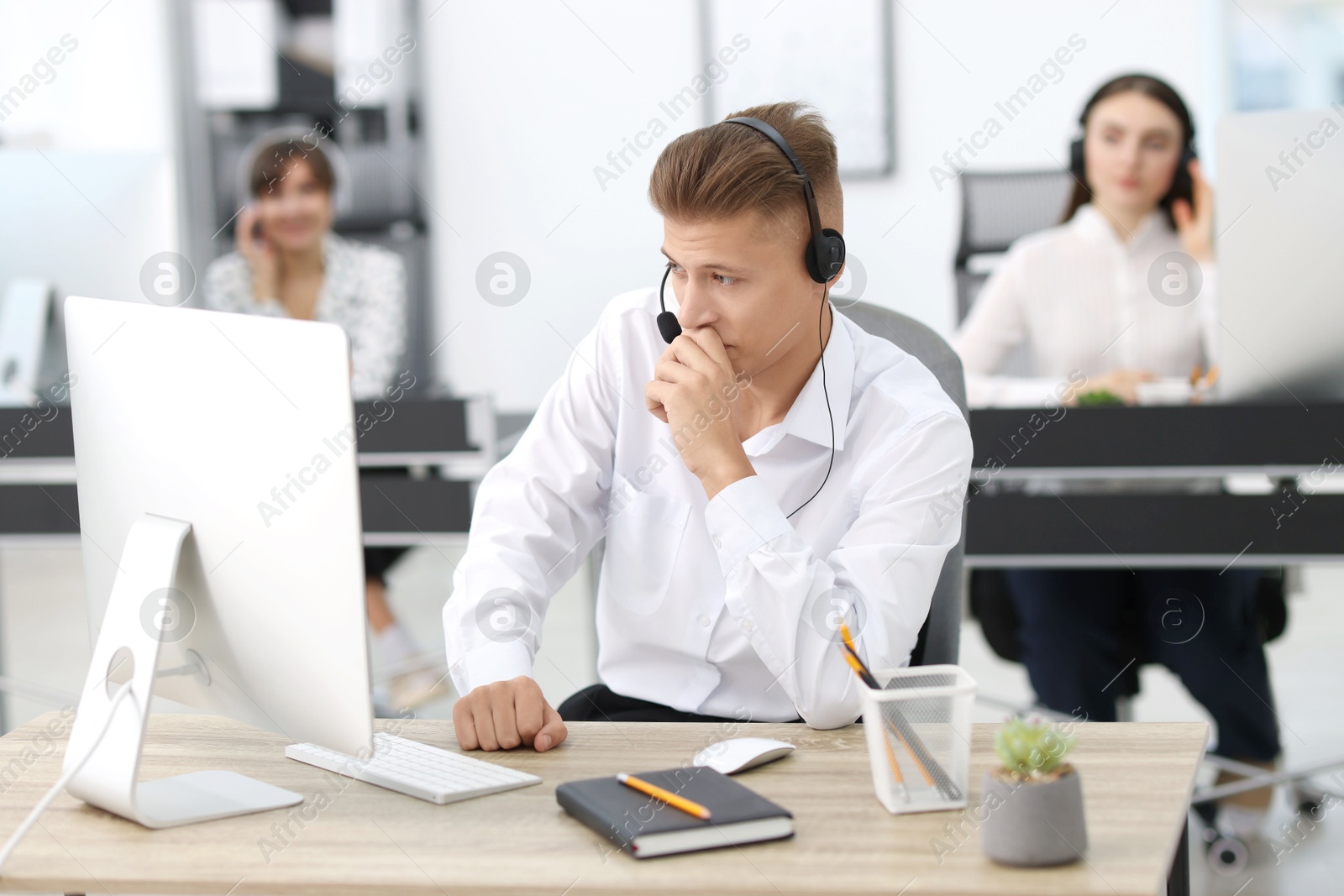 Photo of Salesman talking to client via headset at desk in office