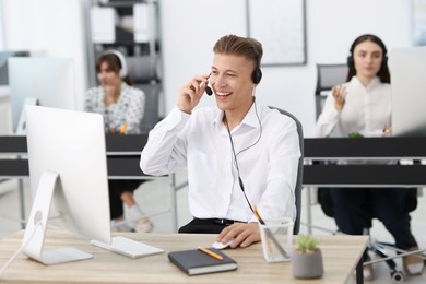 Photo of Salesman talking to client via headset at desk in office