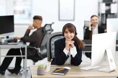 Photo of Saleswoman talking to client via headset at desk in office