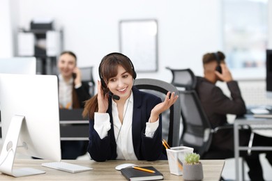 Photo of Saleswoman talking to client via headset at desk in office