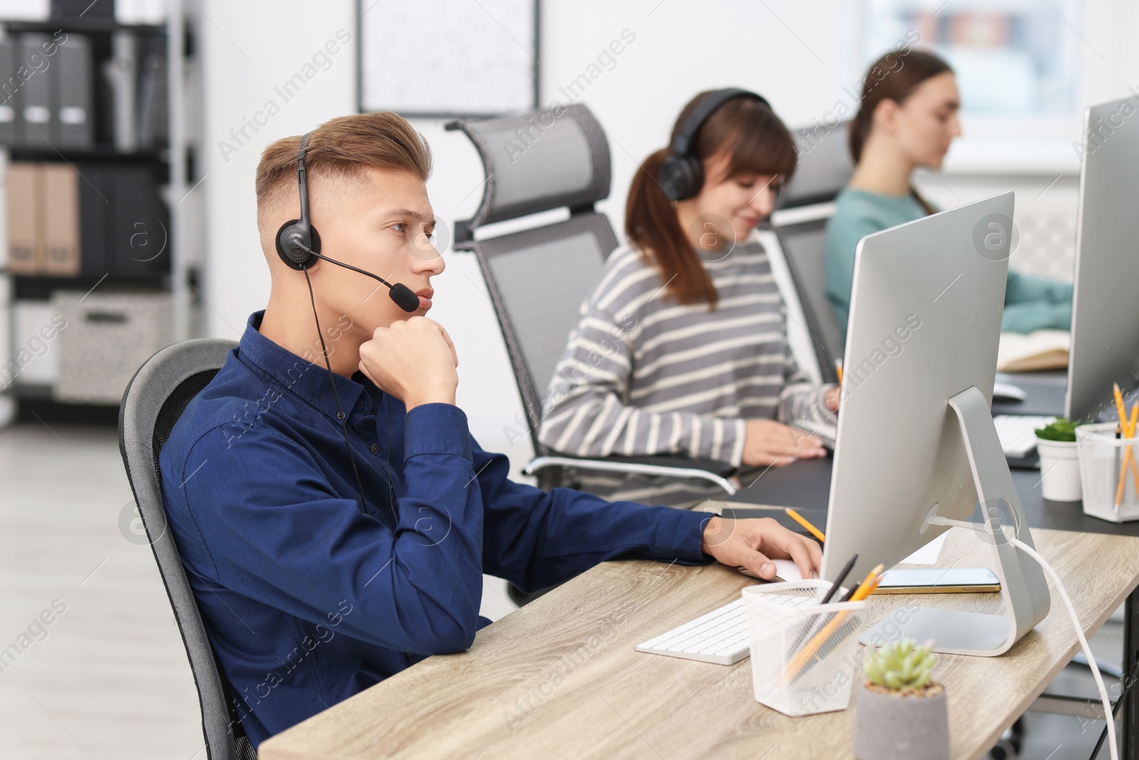 Photo of Salesman talking to client via headset at desk in office