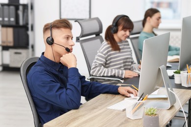 Photo of Salesman talking to client via headset at desk in office