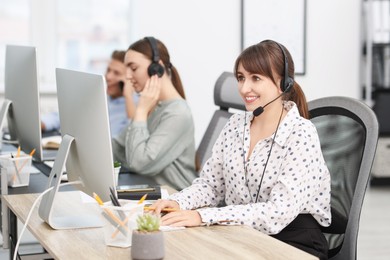 Photo of Saleswoman talking to client via headset at desk in office