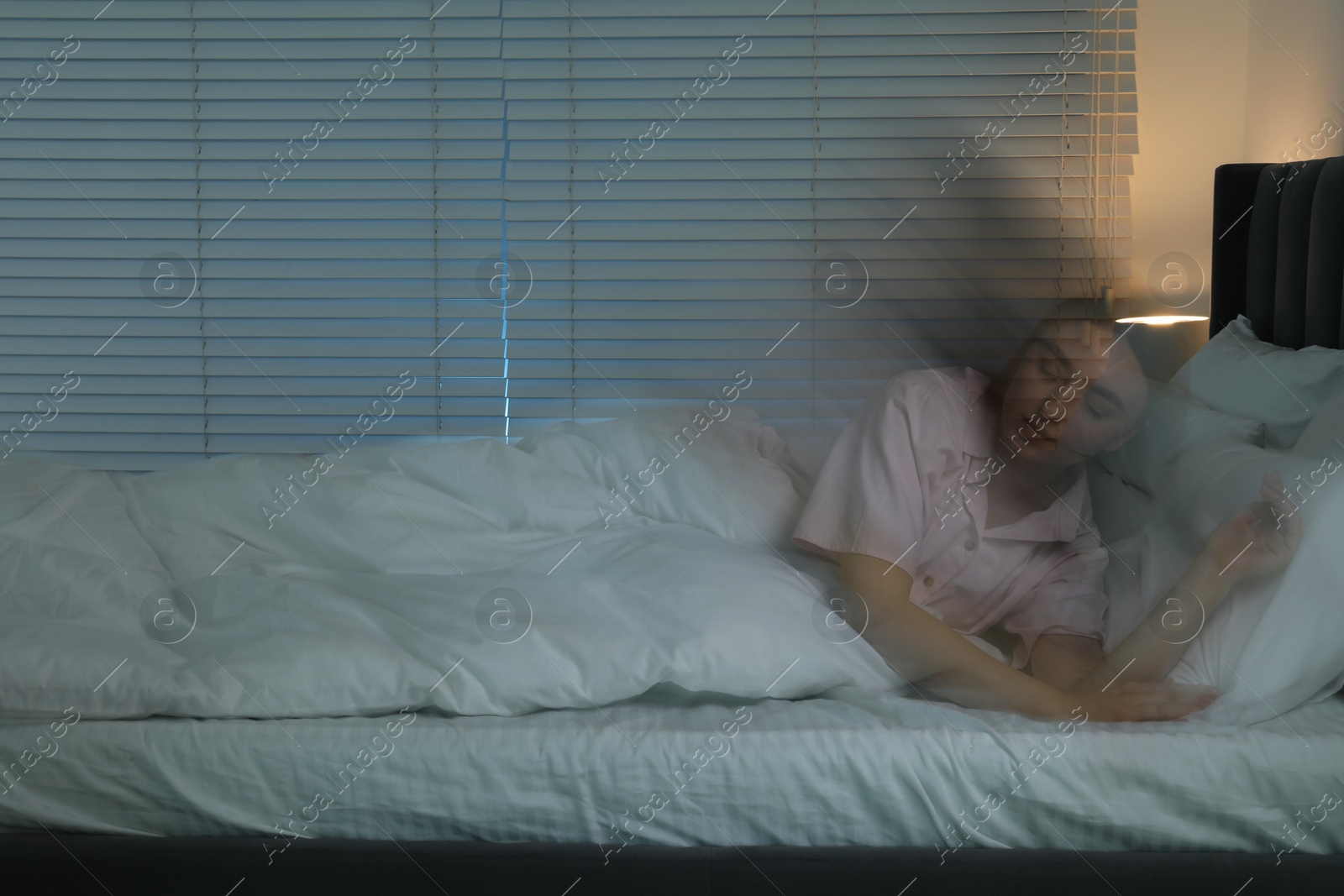 Photo of Young woman suffering from sleepwalking on bed at home, long-exposure