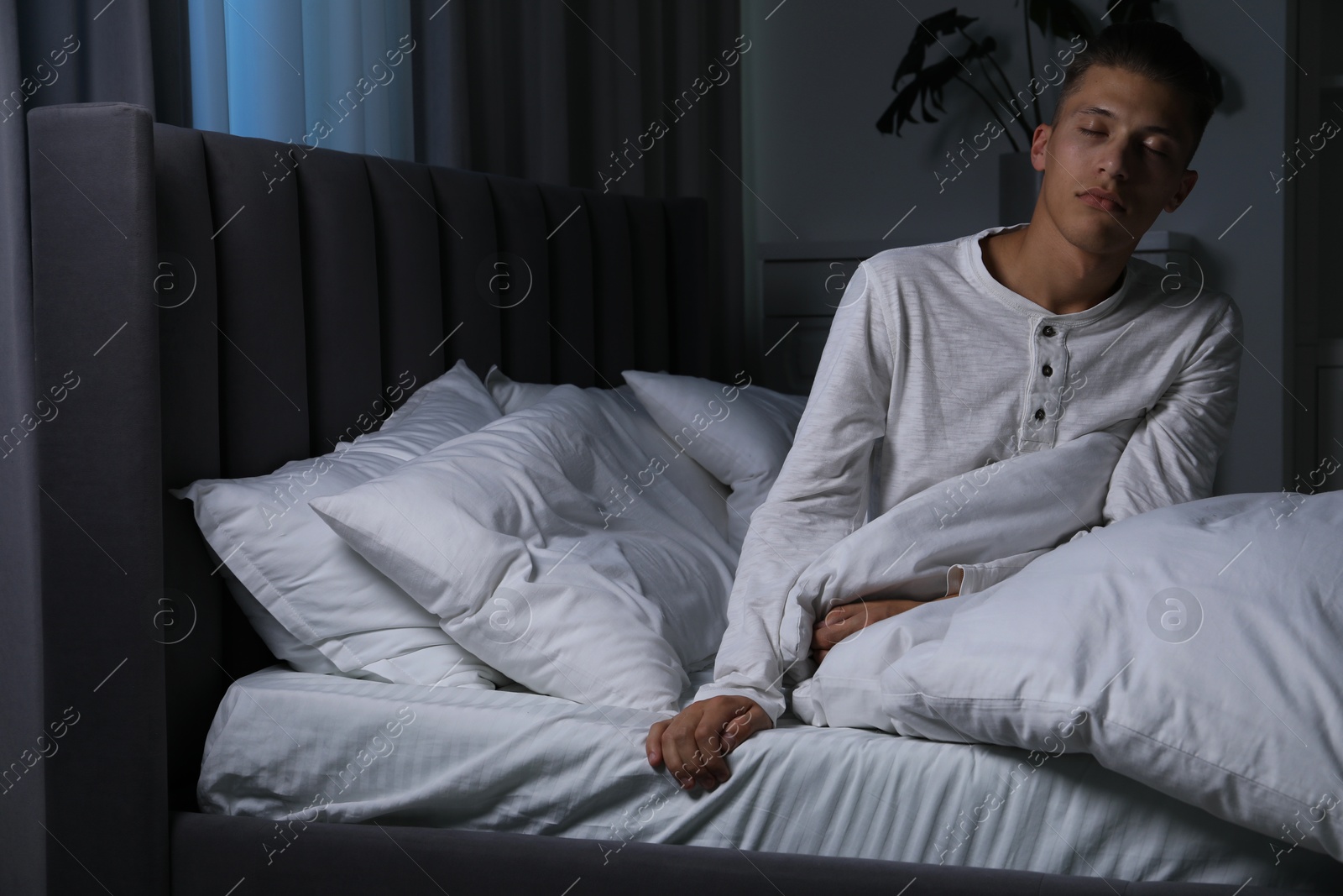 Photo of Young man suffering from sleepwalking on bed at home