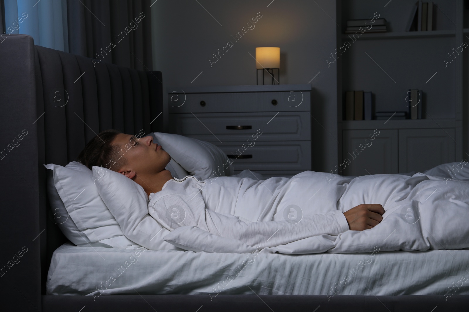 Photo of Young man sleeping in soft bed at night