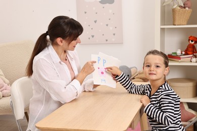 Photo of Speech therapist working with little girl at table in autism treatment center