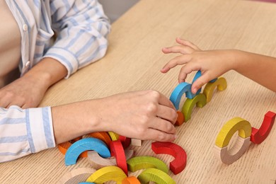 Photo of Autism therapy. Psychologist and little girl playing with educational toy at wooden table, closeup