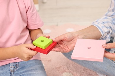 Photo of Autism therapy. Psychologist and little girl playing with educational toy indoors, closeup