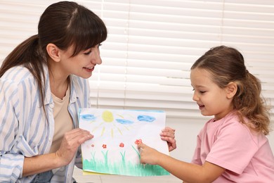 Photo of Smiling therapist working with little girl in autism treatment center