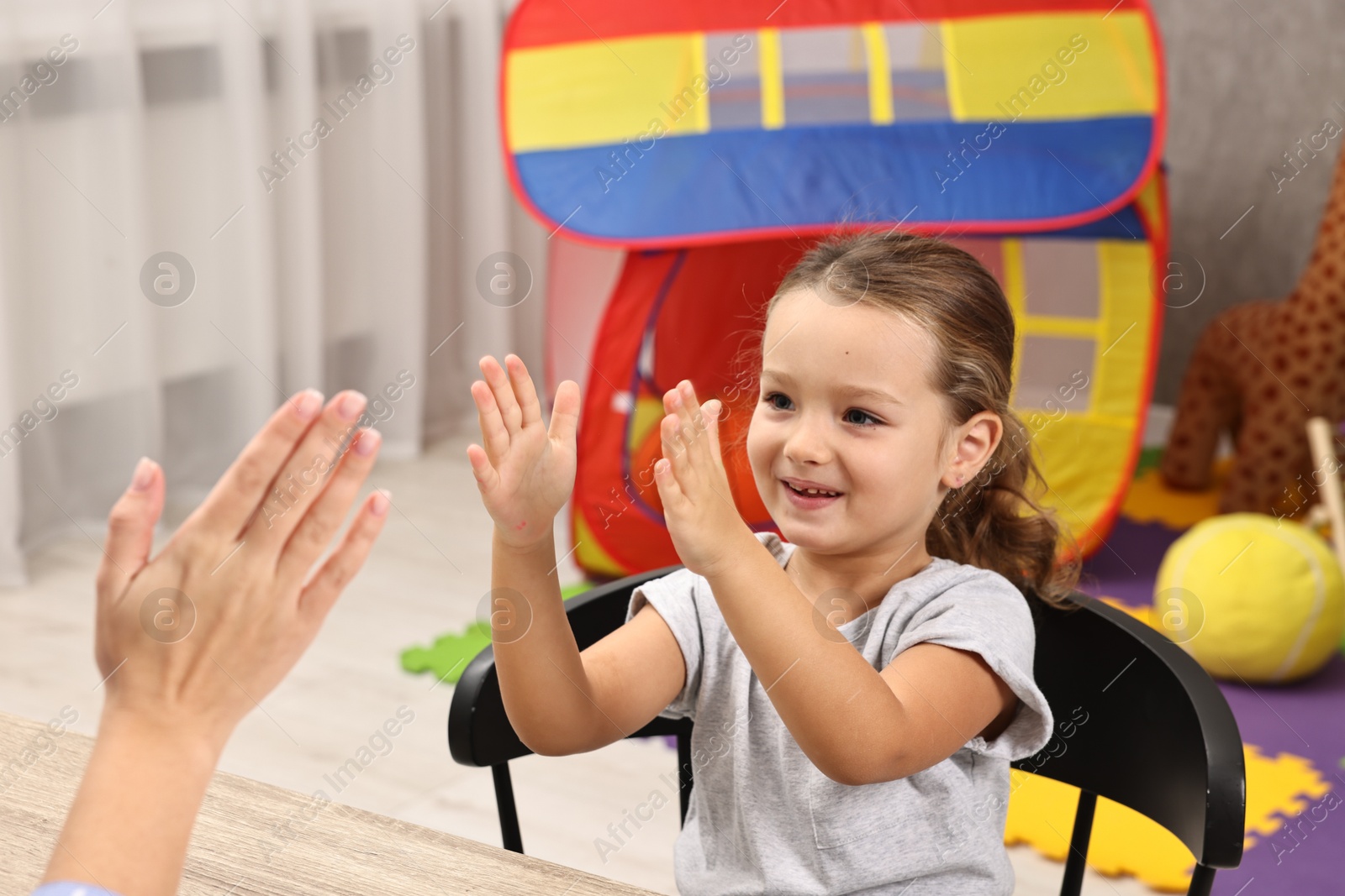 Photo of Autism therapy. Smiling girl playing with psychologist in mental health center