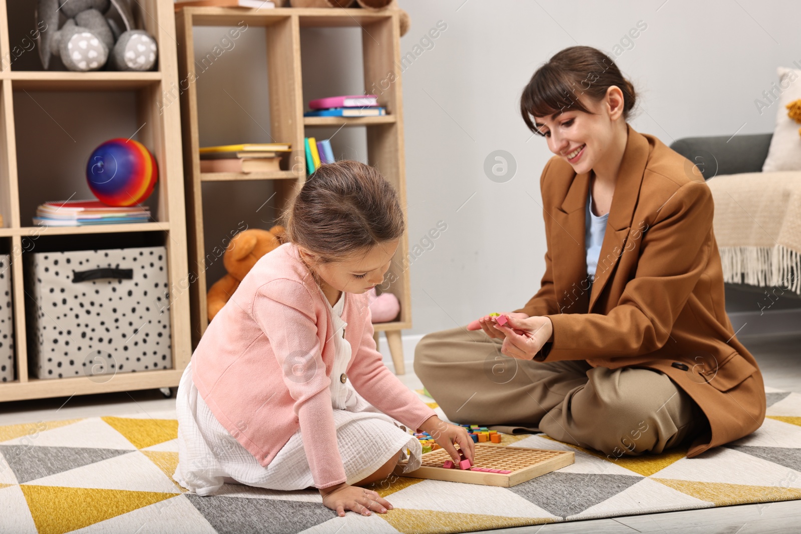 Photo of Autism therapy. Smiling psychologist and little girl playing with educational toy in mental health center