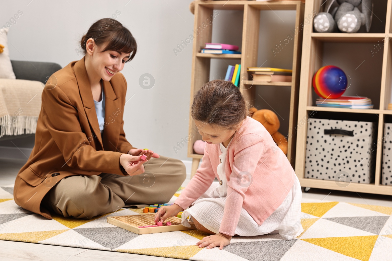 Photo of Autism therapy. Smiling psychologist and little girl playing with educational toy in mental health center