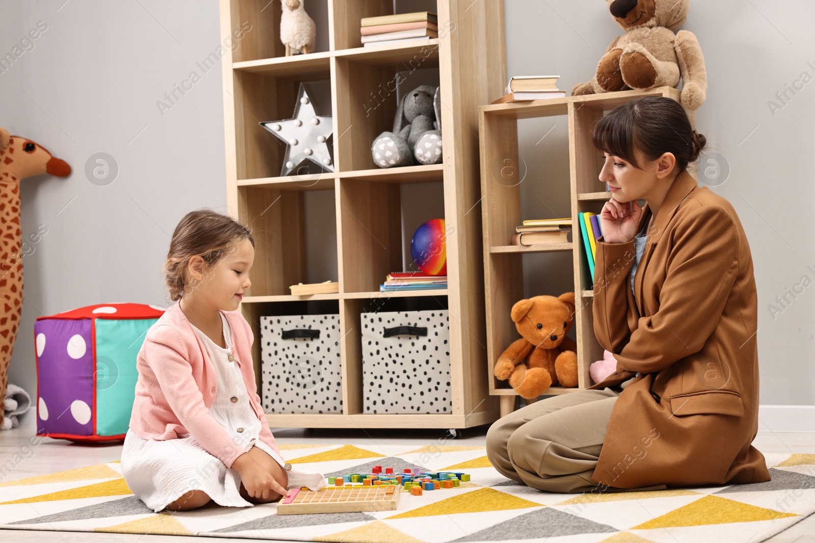 Photo of Therapist observing little girl playing in autism treatment center