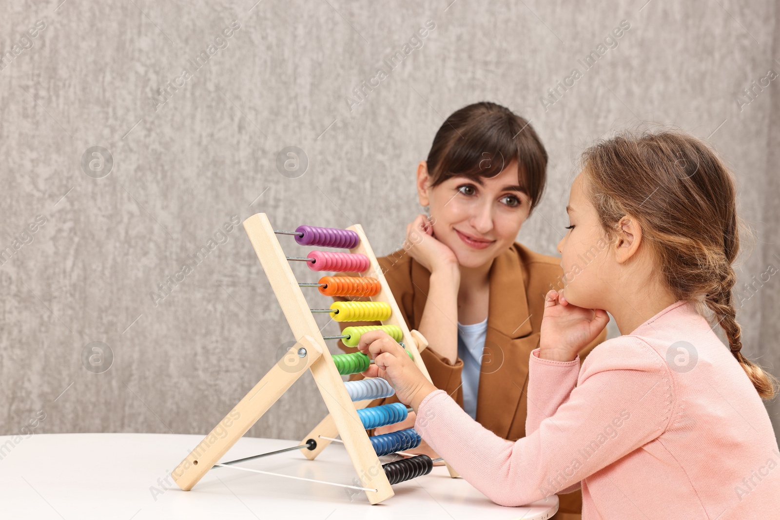 Photo of Autism therapy. Psychologist and girl playing with wooden abacus indoors, space for text