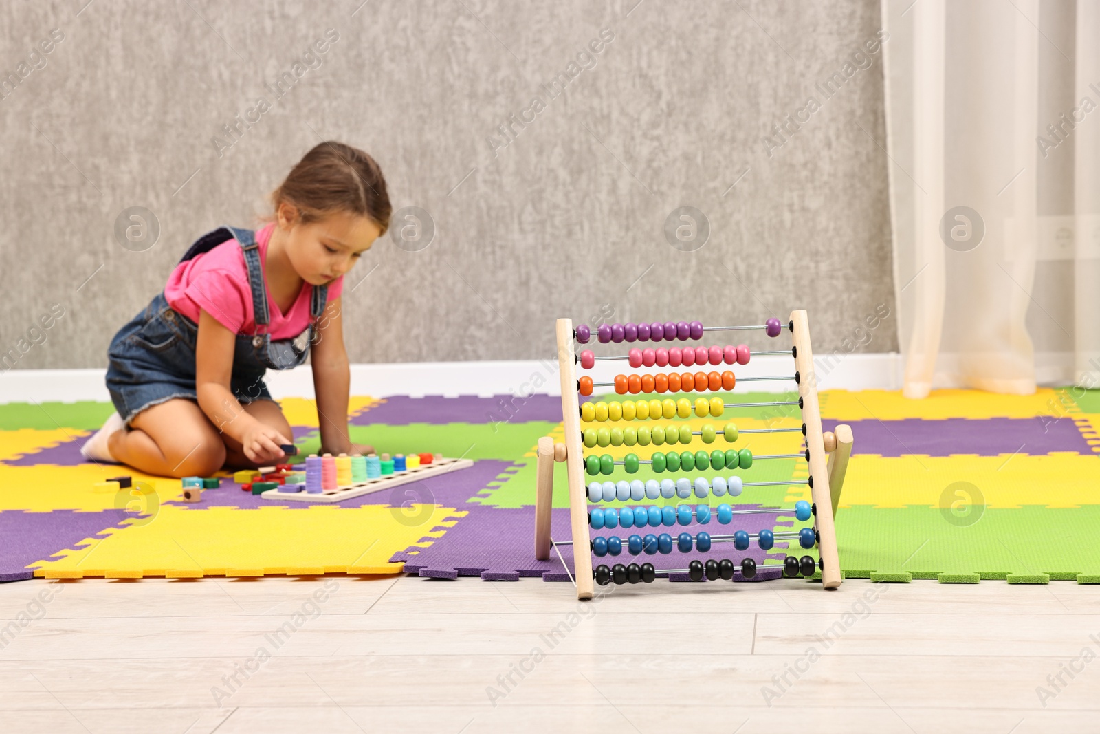 Photo of Autism therapy. Little girl playing with educational toy on floor in mental health center, focus on abacus