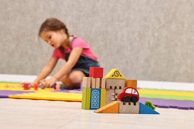 Photo of Autism therapy. Little girl playing on floor in mental health center, selective focus