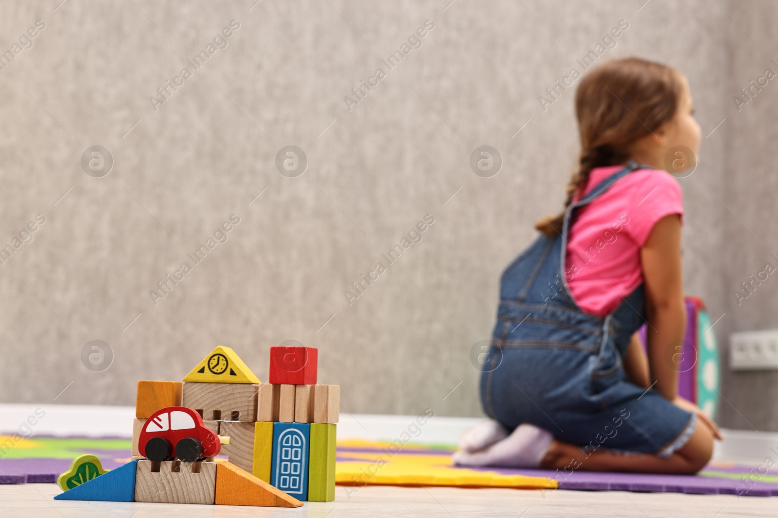 Photo of Autism therapy. Little girl sitting on floor in mental health center, selective focus. Space for text