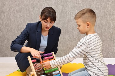 Photo of Autism therapy. Psychologist and little boy playing with abacus in mental health center