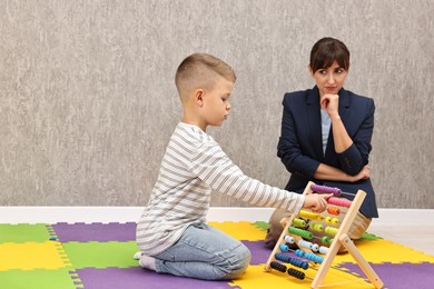 Photo of Psychologist observing little boy playing in autism treatment center. Space for text