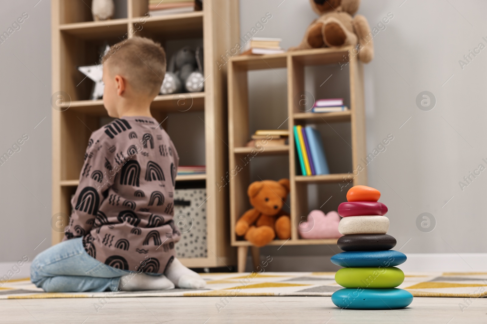 Photo of Autism therapy. Little boy sitting on floor in mental health center, selective focus