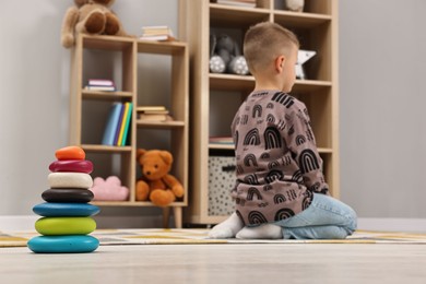 Photo of Autism therapy. Little boy sitting on floor in mental health center, selective focus