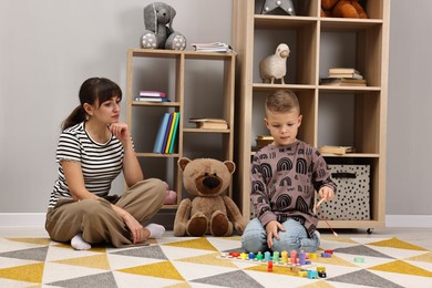 Photo of Psychologist observing little boy playing in autism treatment center