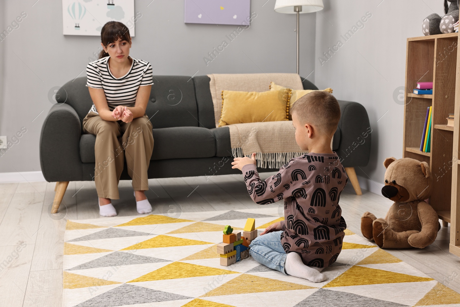 Photo of Psychologist observing little boy playing in autism treatment center