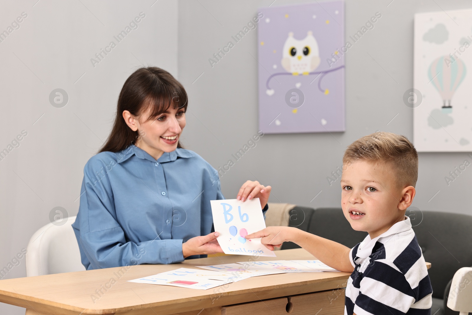 Photo of Smiling speech therapist working with little boy at table in autism treatment center