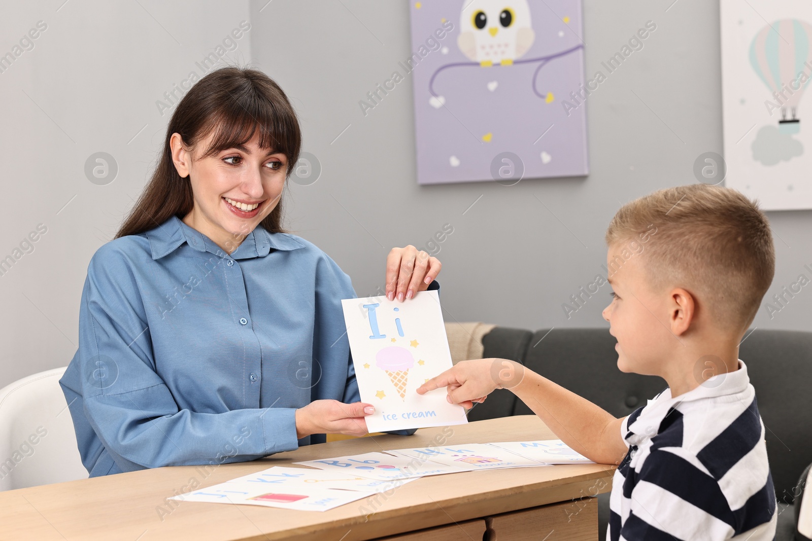 Photo of Smiling speech therapist working with little boy at table in autism treatment center