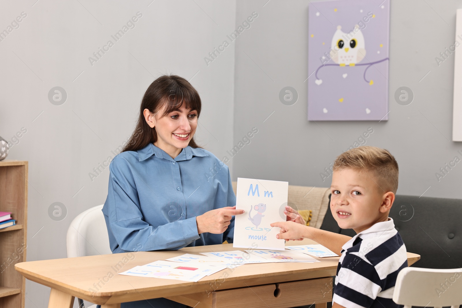 Photo of Smiling speech therapist working with little boy at table in autism treatment center