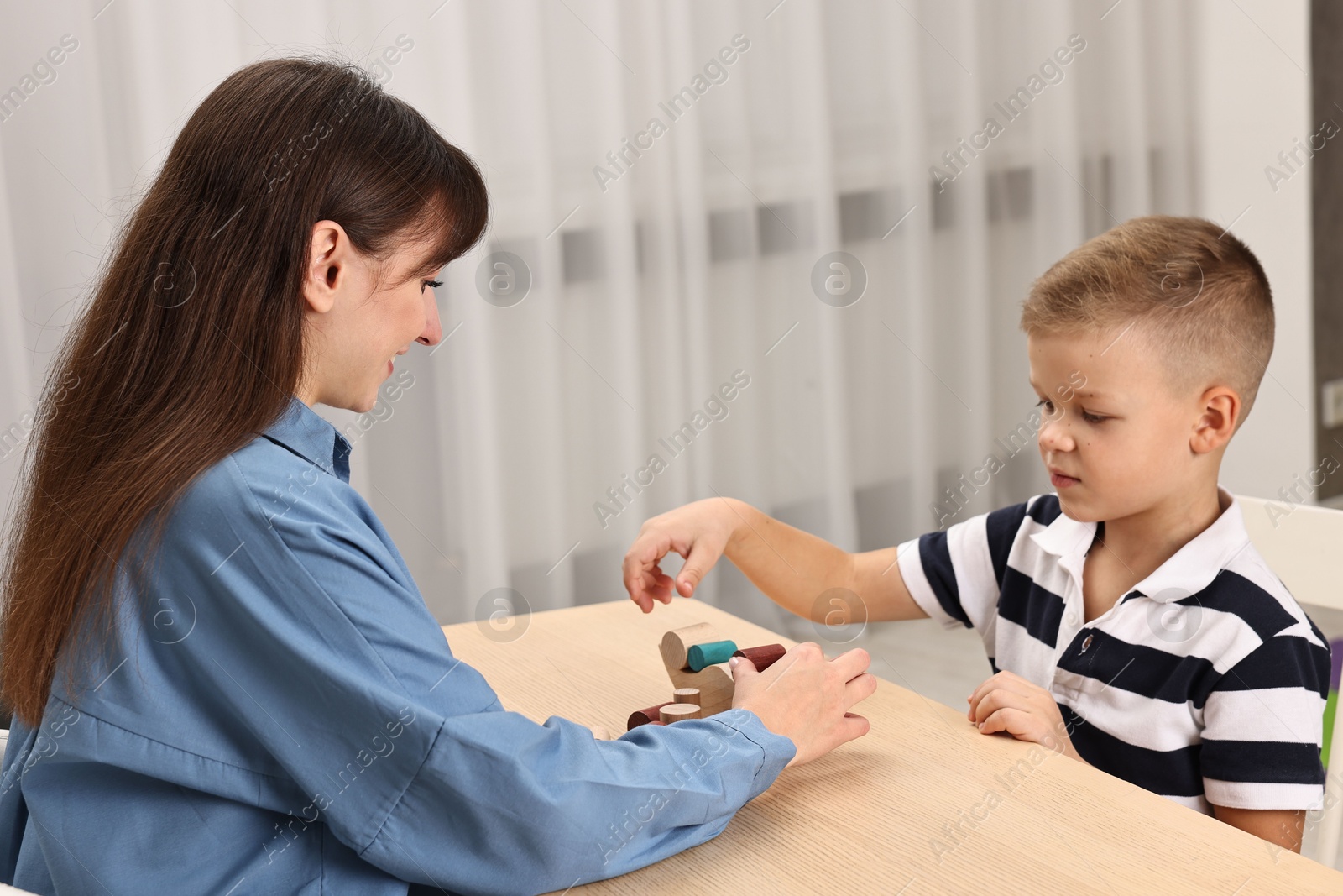 Photo of Autism therapy. Psychologist and little boy playing with educational toy at table in mental health center