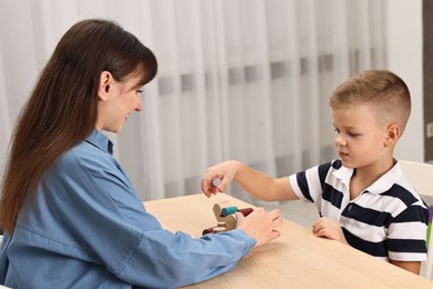 Photo of Autism therapy. Psychologist and little boy playing with educational toy at table in mental health center