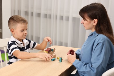 Photo of Autism therapy. Psychologist and little boy playing with educational toy at table in mental health center