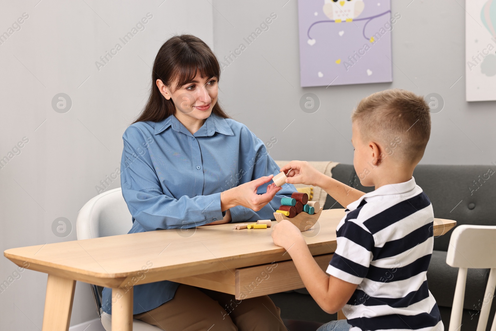 Photo of Autism therapy. Psychologist and little boy playing with educational toy at table in mental health center